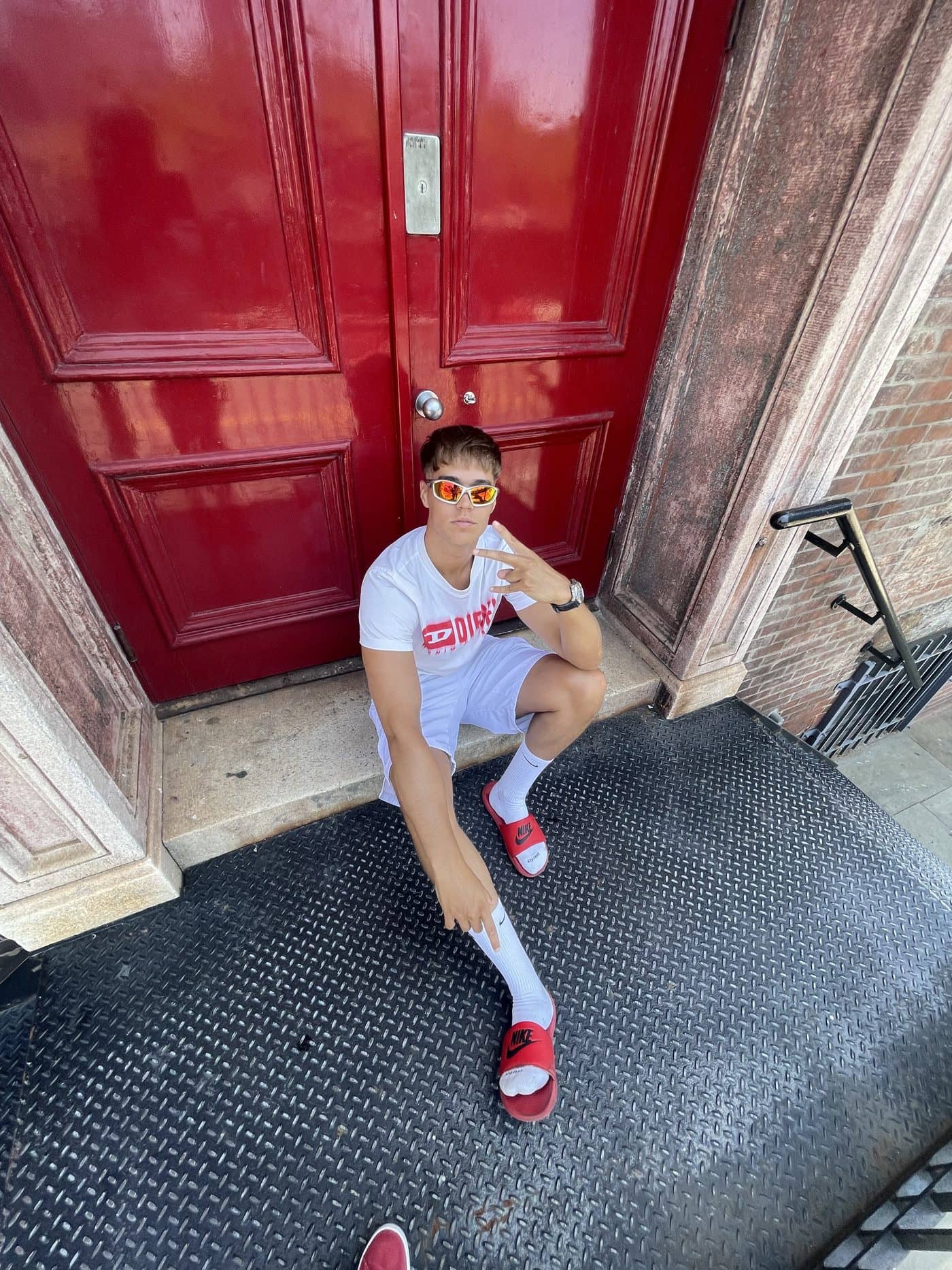 Lucas sitting on the step of a glossy red door in Brooklyn
