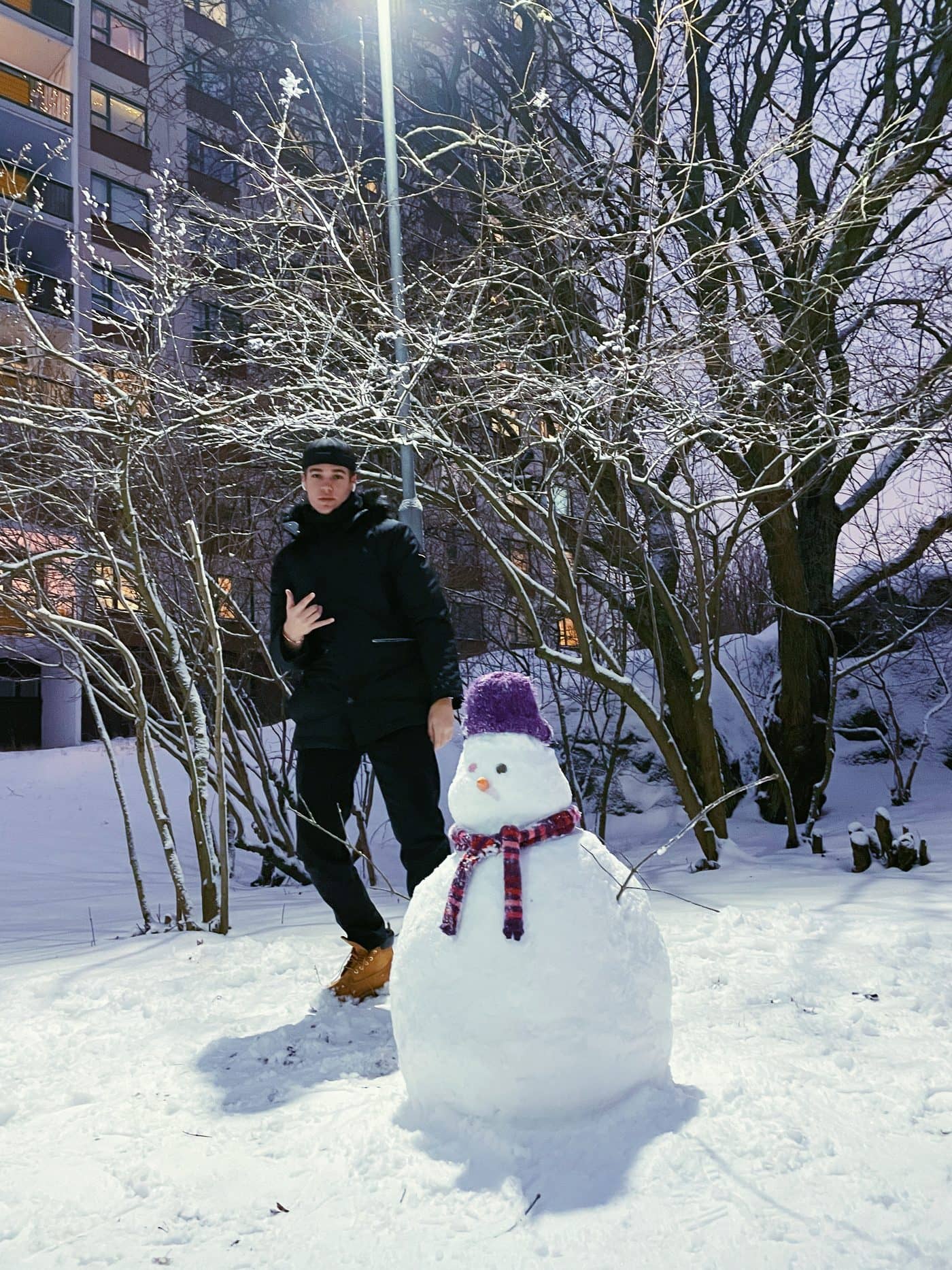 Lucas beside a snowman on a snowy street in Helsinki