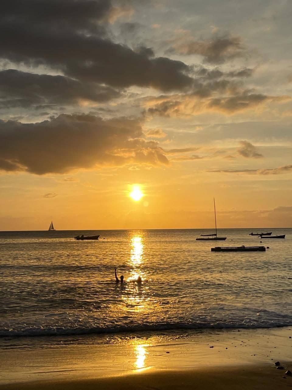 A golden sunset over the sea, with boats on the horizon