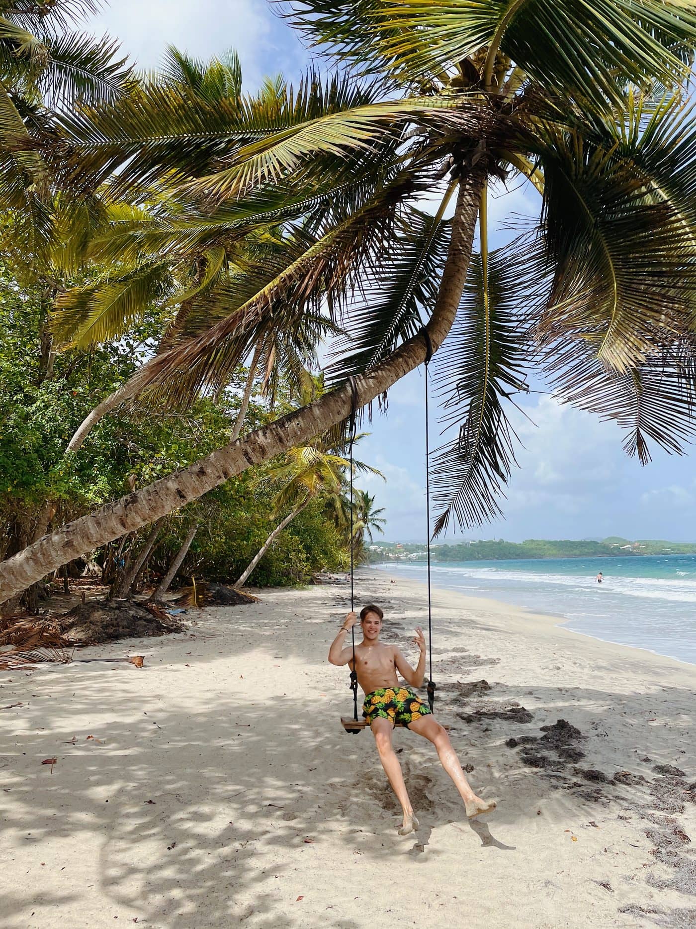 Lucas on a rope swing under palms at Diamant in Martinique