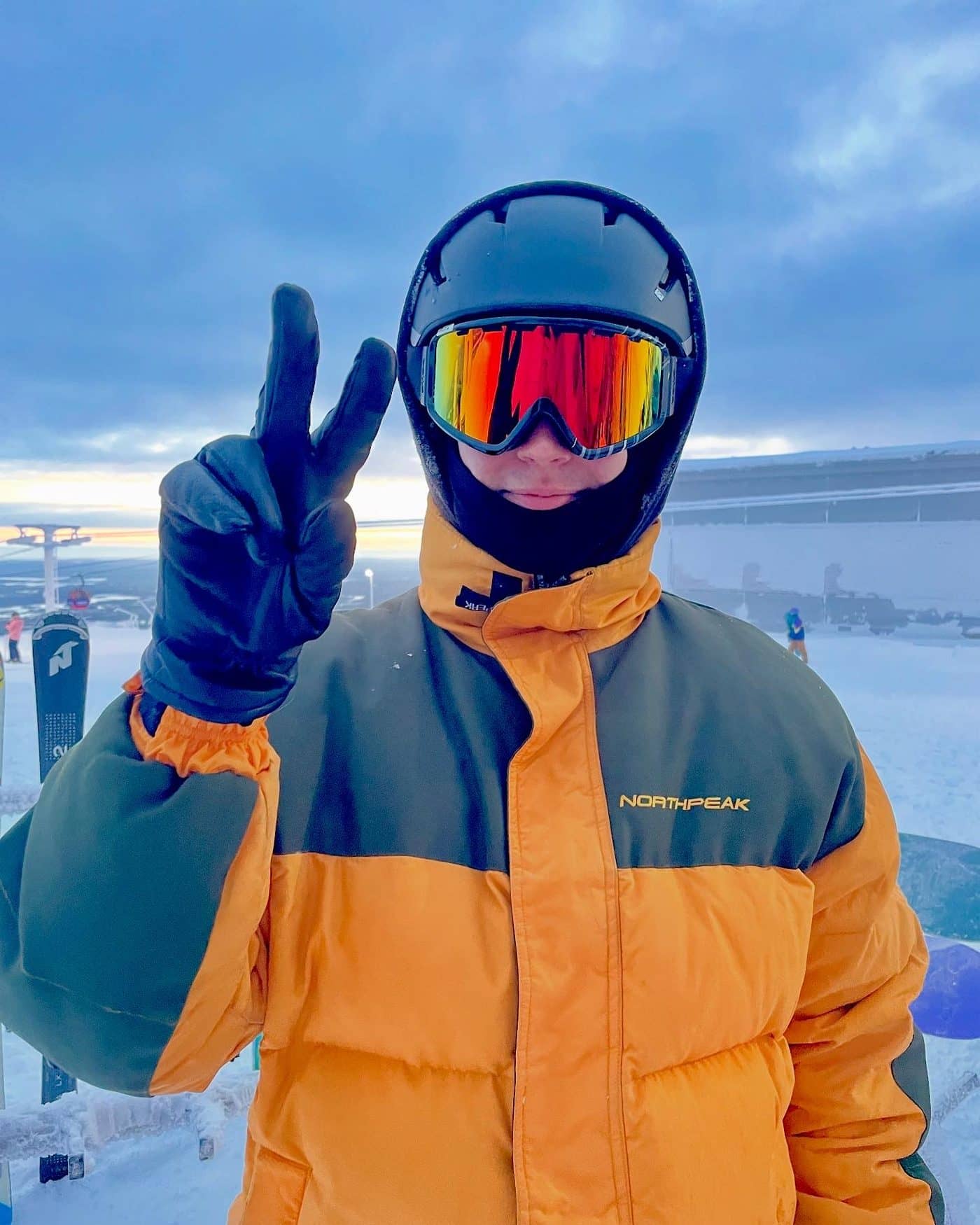 Lucas in ski gear and an orange jacket, making a peace sign