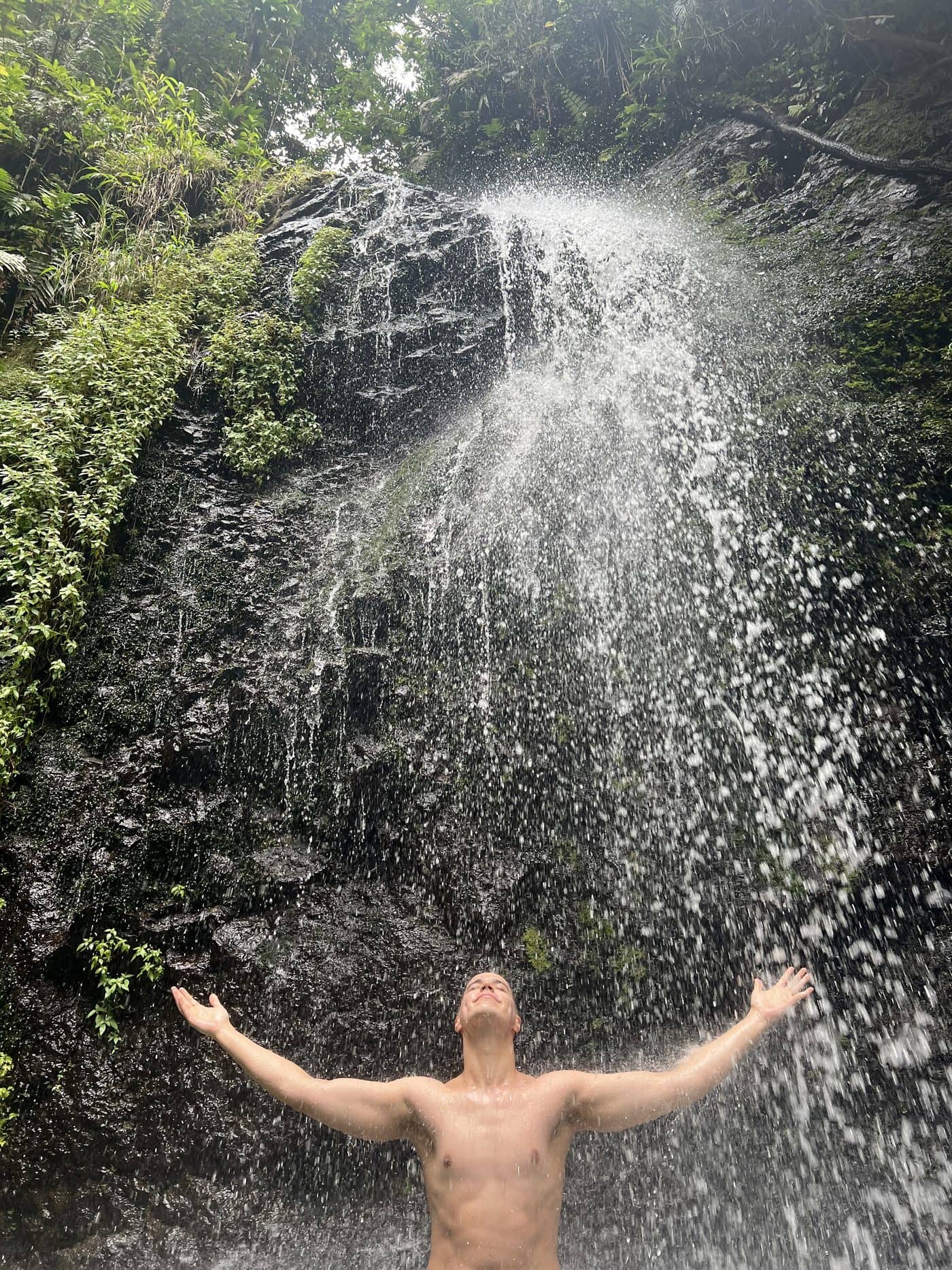 Lucas standing under a waterfall in Martinique